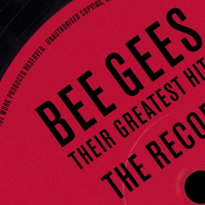 Bee Gees, their greatest hits the record, black font, mostly red background with the top left black, close up shot of a record with the title written over it, 
